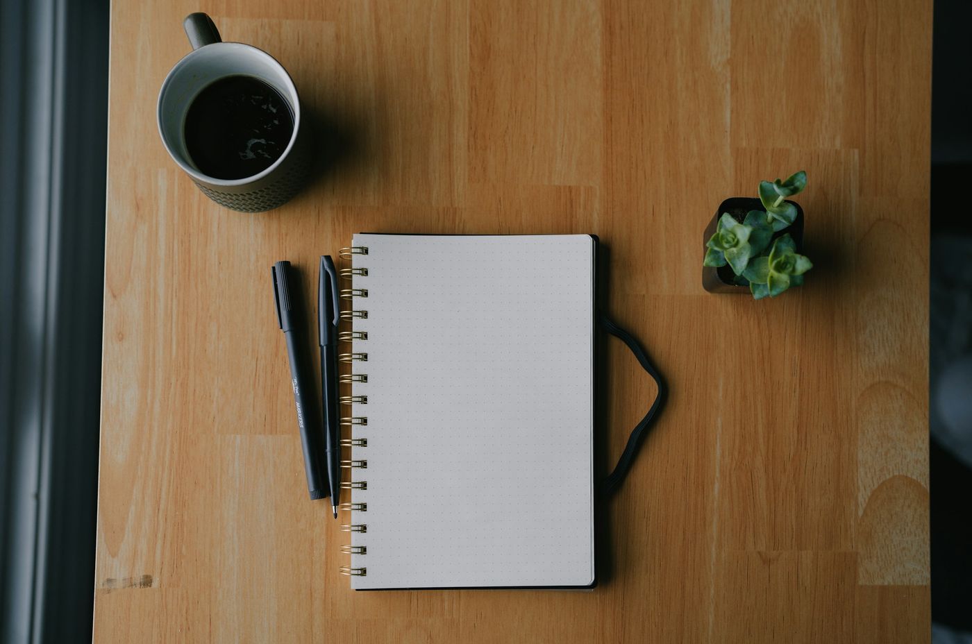 Carnet à spirale, stylos et tasse de café sur une table en bois