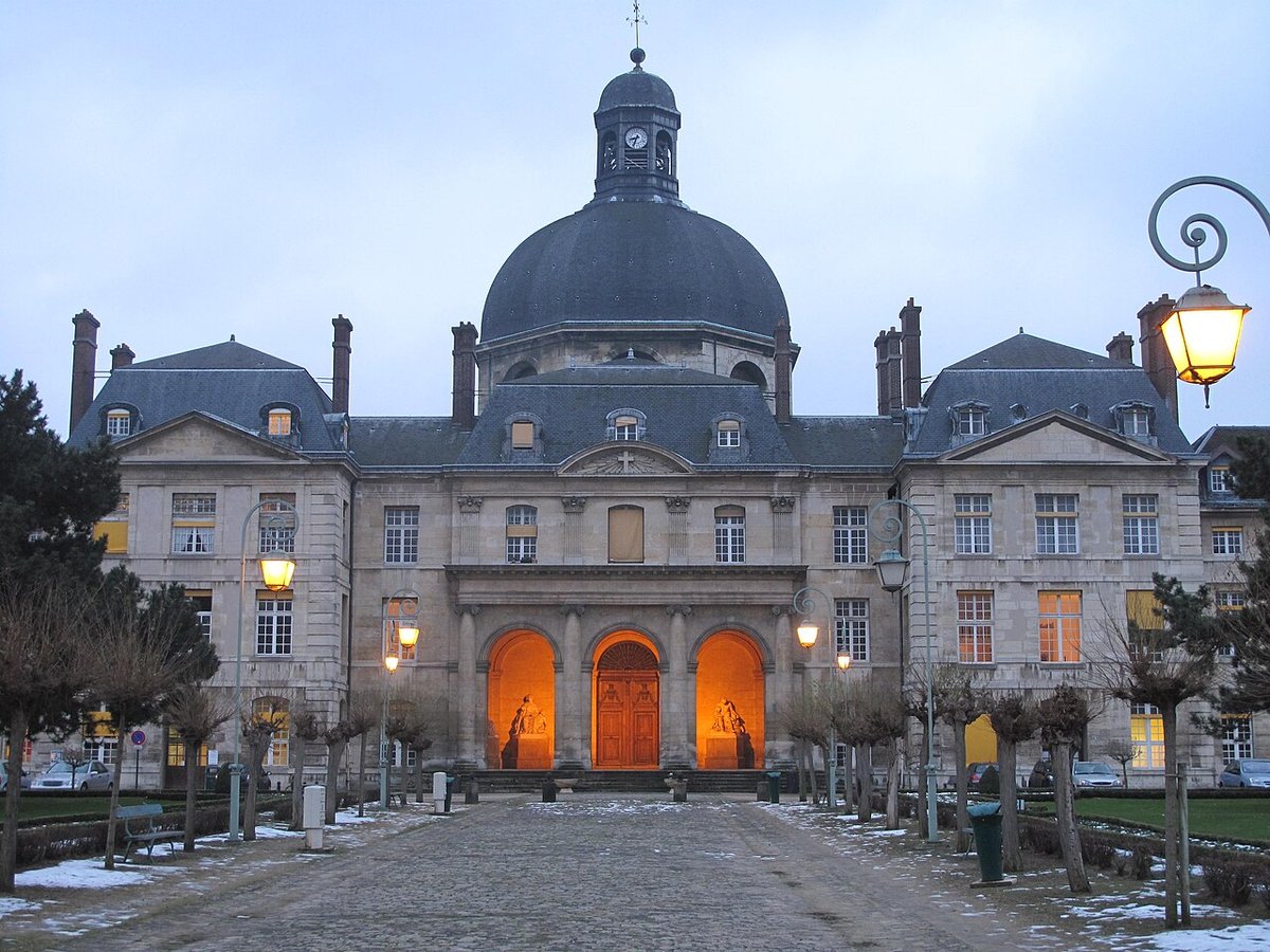 Façade et dôme de la chapelle de la Salpêtrière à Paris à l'aube, lampadaires allumés et allée pavée enneigée